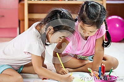 Two asian little girls having fun to paint with crayon Stock Photo