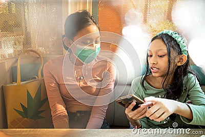 Two Asian teen girls hangout together with only one of them wearing face mask Stock Photo