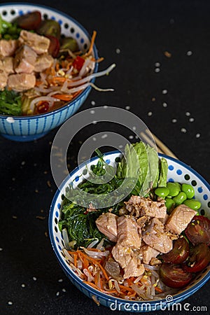 Two assorted bowls with salmon, vegetables, and rice. Hawaiian Poke cuisine Stock Photo