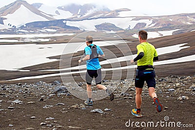 Two athlete runners run a mountain marathon in the snowy terrain of Landmannalaugar. Iceland Editorial Stock Photo