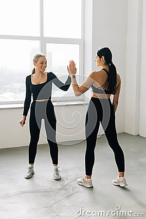 Two athletic beautiful women friend give high five in the gym Stock Photo