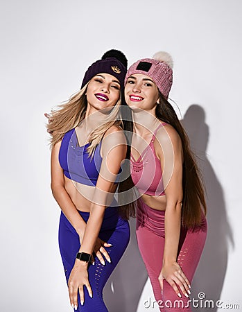 Attractive, young and fit women with long hair wearing sports clothing and knitted hats over a white background Stock Photo