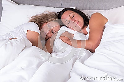 Two attractive women sleeping next to each other in bed Stock Photo