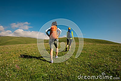 Backpacking women friends hiking in grassland mountains Stock Photo