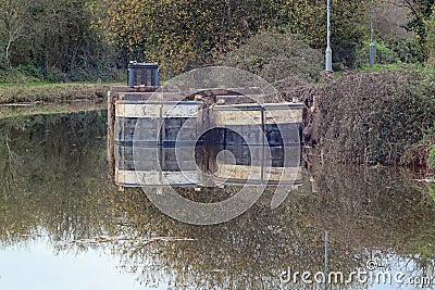 Two barges moored on a murky canal in England, filled with mud from a dredger Stock Photo