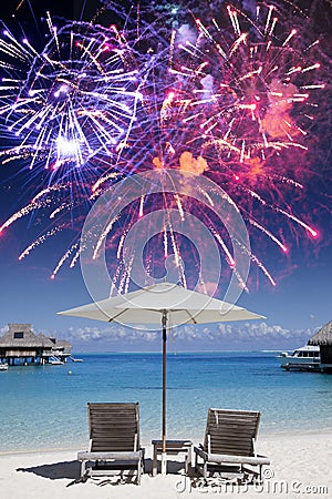Two beach chairs in the sand by the sea and fireworks in the dark blue sky, mixed media Stock Photo