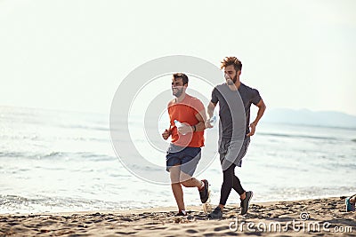 Two guys running along the beach coast Stock Photo