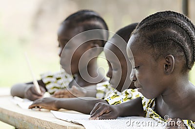 Two beautiful African girls and one African boy reading and writ Stock Photo