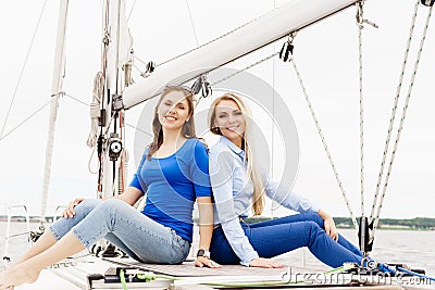 Two beautiful, attractive young girls a hiving a rest on yacht. Stock Photo