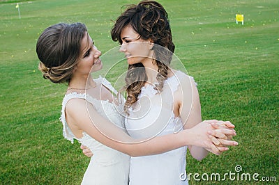 Two beautiful brides dancing on the green field Stock Photo