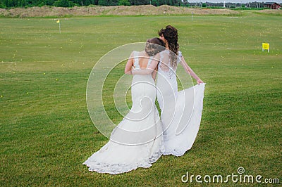 Two beautiful brides embracing on the green field Stock Photo