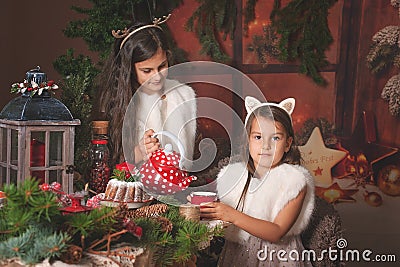 Two beautiful children, sisters, having Christmas party at family wooden cottage, cozy Christmas atmosphere. Stock Photo