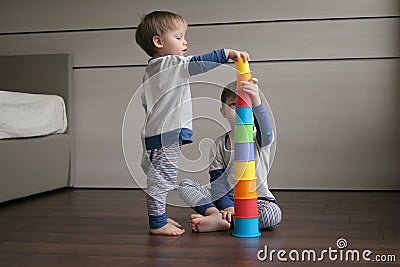 Two beautiful, similar boys collect a bright pyramid. Stock Photo