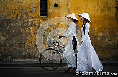 Two beautiful Vietnamese women in traditional Ao Dai dress riding a bicycle Editorial Stock Photo