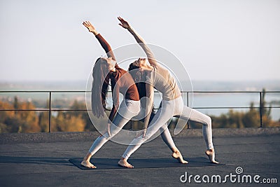 Two beautiful women perform double pose warrior with raised hand Stock Photo