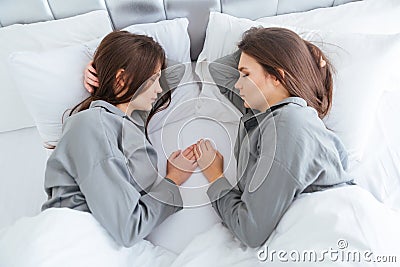 Two beautiful young sisters twins sleeping on bed together Stock Photo