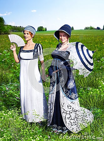 Two beautiful young women dressed in Victorian Regency Jane Austen style fashion dresses Stock Photo