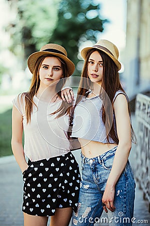 Two beautiful young women in hats having fun in the city. Warm summer. Girls in sunglasses. Stock Photo