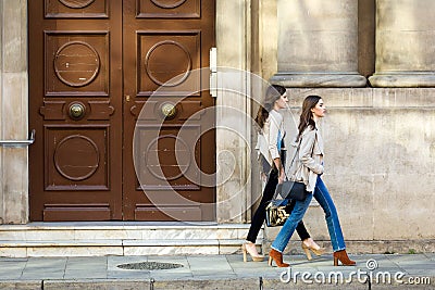 Two beautiful young women walking and talking in the street. Stock Photo