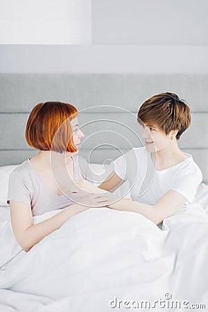 Two best female friends talking while resting on the bed indoors Stock Photo