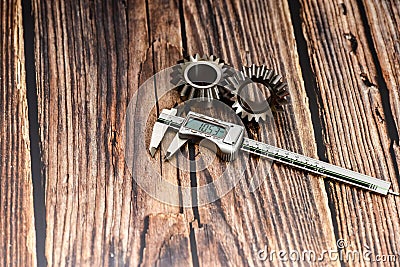 Two bevel gears and vernier caliper on a wooden background Stock Photo