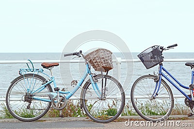 Two bicycles chained to the fence of promenade in Southwold, UK Stock Photo