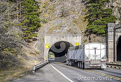 Two big rig commercial long haul semi trucks running in the tunnel towards each other Stock Photo