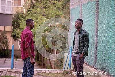 Two black race friends conversing in the street. Friends Concept. Stock Photo