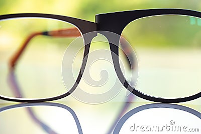 Two black shortsighted or nearsighted eyeglasses on white acrylic table, Bokeh green garden background, Reflection, Optical Stock Photo