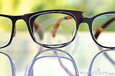 Two black shortsighted or nearsighted eyeglasses on white acrylic table, Bokeh green garden background, Reflection, Optical Stock Photo