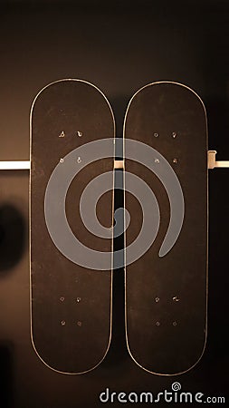 Two black skate board hanging at the black painted wall Stock Photo