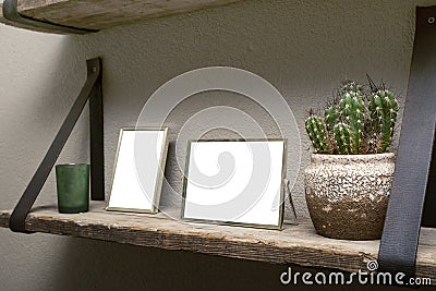 Two blank picture frames and cactus decoration on wooden shelf, industrial retro interior design Stock Photo