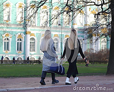 Two blonde girls in warm clothes carry a blue bag Editorial Stock Photo