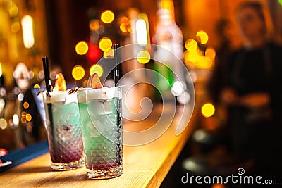 Two blue cocktails with lemon on the bar, blurred background. Stock Photo