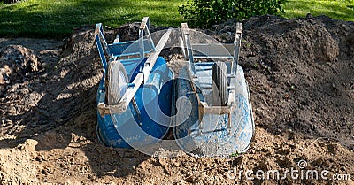 Two blue dirty wheelbarrows turned upside down in the dirt Stock Photo