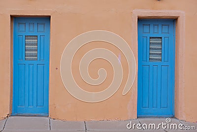 Two blue doors as entrances to a brown stucco building Stock Photo