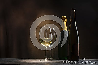 Two bottles with two glasses of wine on a wooden table in the dark of the night Stock Photo