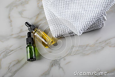 Two bottles of green natural serum and yellow organic beauty face oil for cosmetic anti age treatment skin care on towels and Stock Photo