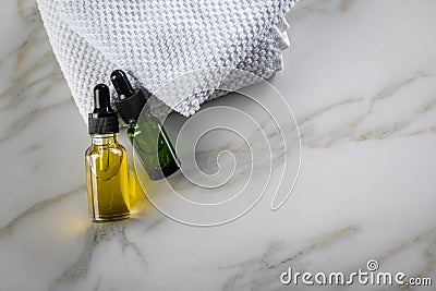 Two bottles of green natural serum and yellow organic beauty face oil for cosmetic anti age treatment skin care on towels and Stock Photo