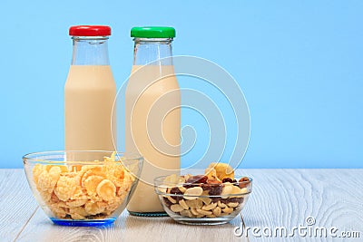 Two bottles of milk with red and green cap and bowls with muesli and cornflakes Stock Photo