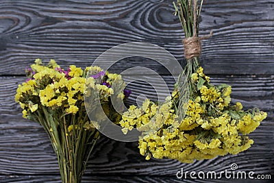 Two bouquets of statice. One is yellow, the other is multi-colored. Against the background of pine boards Stock Photo