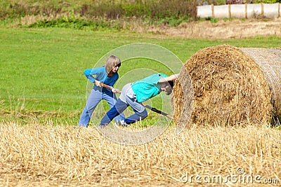 Two Boys Moving Bale of Hay Stock Photo