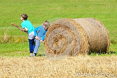 Two Boys Moving Bale of Hay Stock Photo