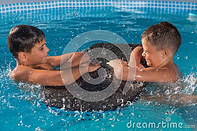 Two boys play in the pool, a lot of splashes and drops of water, a childhood Stock Photo