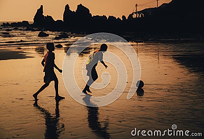 Two boys play soccer on beach in dusk, Goa, India Editorial Stock Photo