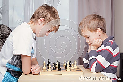 Two boys playing chess at home Stock Photo