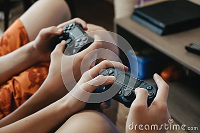 Two Boys playing online video game on playstation. Two teenager holding Joystick in front of the monitor screen Editorial Stock Photo