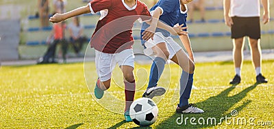 Two Boys Running After Ball on Practice Field. Coach Standing in the Background Stock Photo