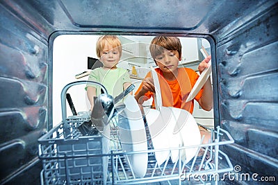 Two boys together take dishes form the dishwasher Stock Photo