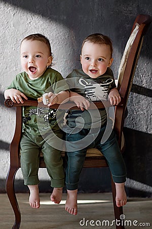 Two boys twins at the age of one year sitting next on the armchair Stock Photo